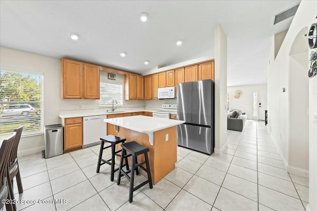 kitchen featuring white appliances, light tile patterned floors, light countertops, and a sink