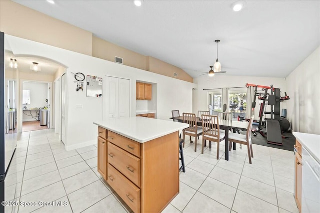 kitchen with a kitchen island, arched walkways, light tile patterned flooring, light countertops, and ceiling fan