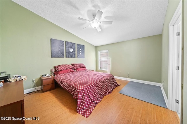 bedroom with baseboards, lofted ceiling, a textured ceiling, and wood finished floors