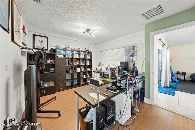 home office with wood finished floors, visible vents, and a textured ceiling