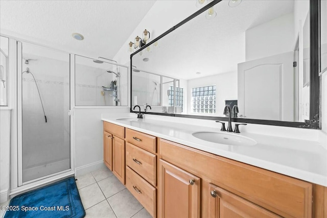 full bath featuring tile patterned floors, double vanity, a stall shower, and a sink