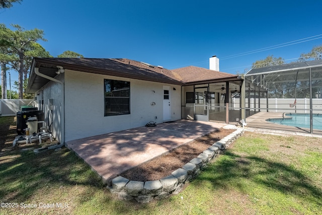 rear view of house with a patio, fence, stucco siding, a lanai, and a lawn