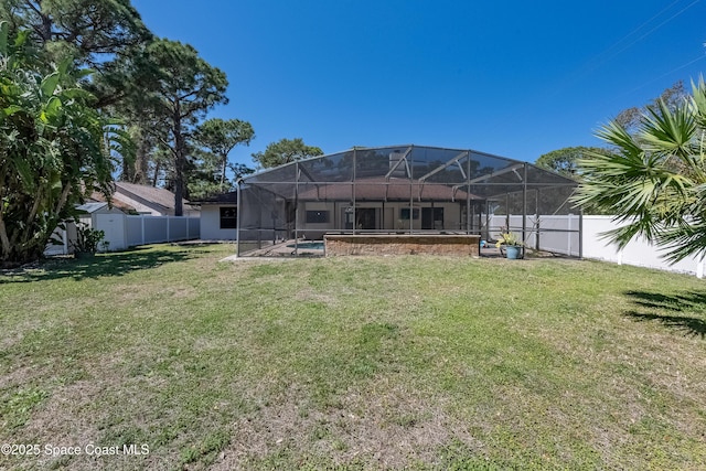 rear view of house featuring a lanai, a lawn, an outdoor structure, and a fenced backyard