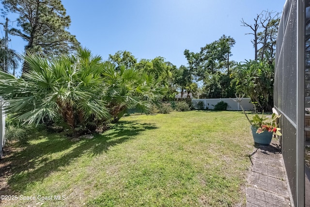 view of yard featuring glass enclosure and a fenced backyard