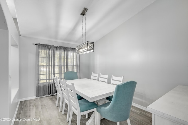 dining room with vaulted ceiling, baseboards, and light wood-type flooring