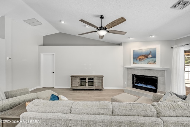 living room featuring visible vents, a tile fireplace, lofted ceiling, and wood finished floors