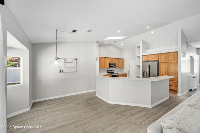 kitchen with open floor plan, light countertops, vaulted ceiling with skylight, appliances with stainless steel finishes, and light wood-style floors