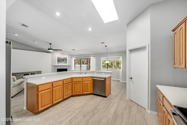 kitchen with open floor plan, light wood-style floors, appliances with stainless steel finishes, a fireplace, and light countertops