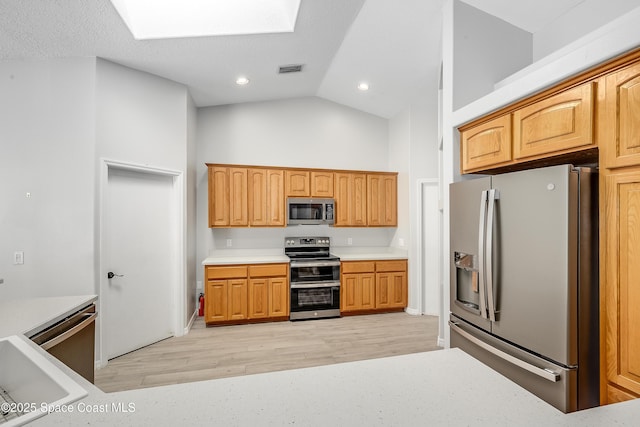 kitchen with visible vents, appliances with stainless steel finishes, a skylight, light wood finished floors, and light countertops