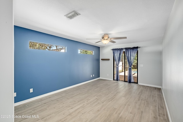 unfurnished room with ceiling fan, visible vents, a healthy amount of sunlight, and wood finished floors