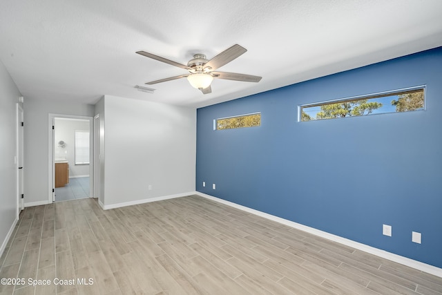 spare room with ceiling fan, visible vents, a wealth of natural light, and light wood-type flooring