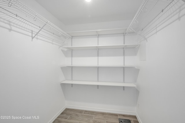 walk in closet with wood finish floors