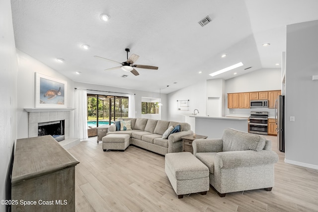 living area featuring lofted ceiling, light wood-style floors, and visible vents