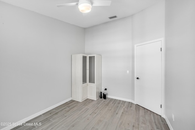 spare room with baseboards, light wood-type flooring, and ceiling fan