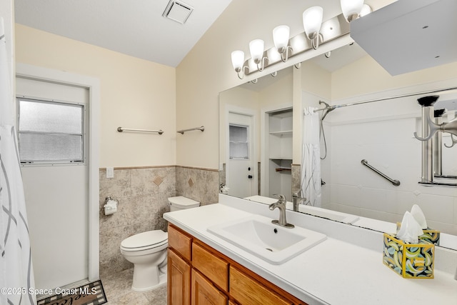 full bath with visible vents, toilet, tile walls, wainscoting, and vanity