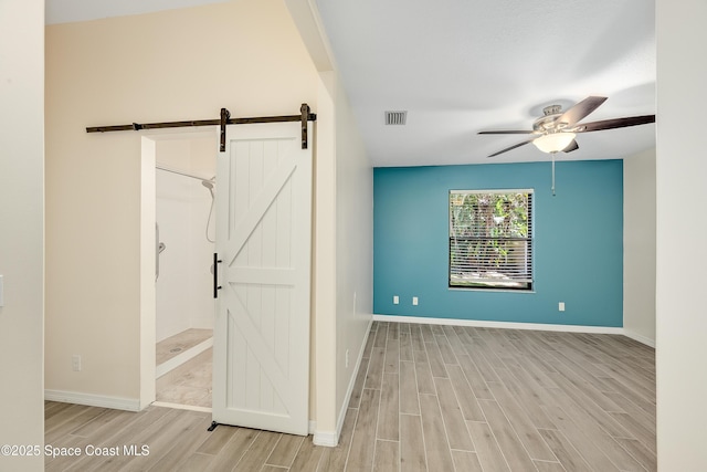 empty room with visible vents, a barn door, and wood tiled floor