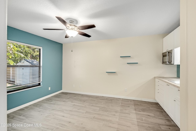 unfurnished room with light wood-style flooring, baseboards, and ceiling fan