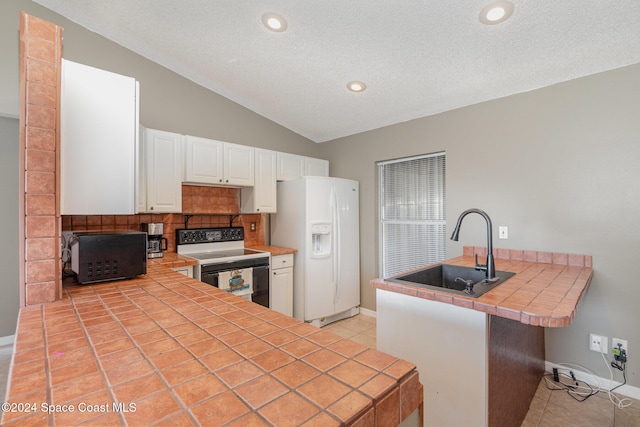 kitchen with tile countertops, electric range oven, a peninsula, white refrigerator with ice dispenser, and a sink