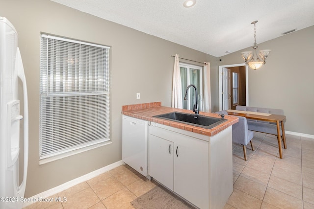 kitchen with white appliances, light tile patterned floors, a peninsula, a sink, and vaulted ceiling