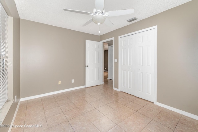 unfurnished bedroom with a closet, visible vents, baseboards, and light tile patterned floors