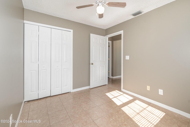 unfurnished bedroom with light tile patterned floors, visible vents, baseboards, and a closet