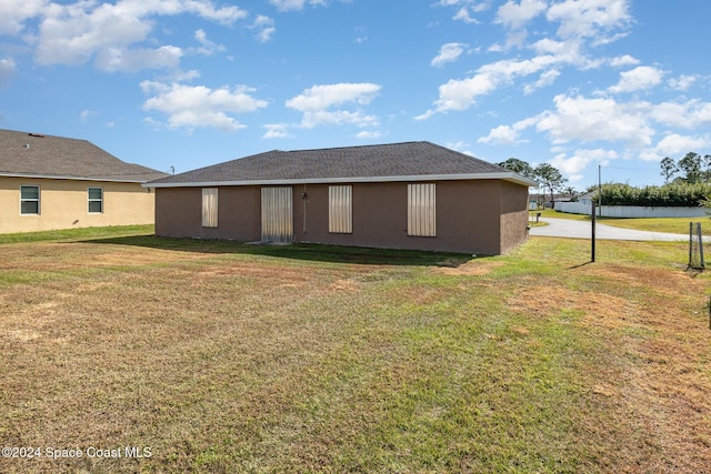 back of property with stucco siding and a yard