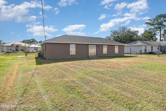 back of property with central air condition unit, a lawn, and stucco siding