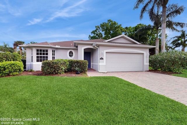 ranch-style house featuring stucco siding, decorative driveway, a garage, and a front yard