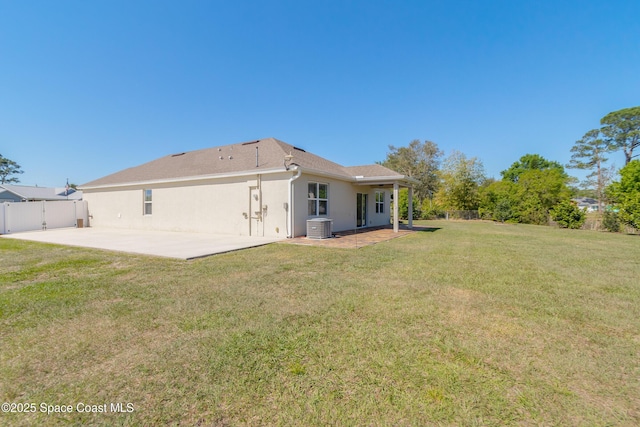 rear view of property featuring a patio, a gate, fence, stucco siding, and a lawn