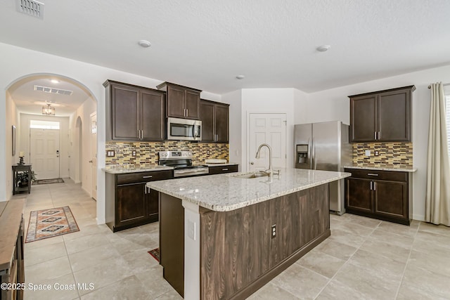 kitchen with arched walkways, visible vents, stainless steel appliances, and a sink