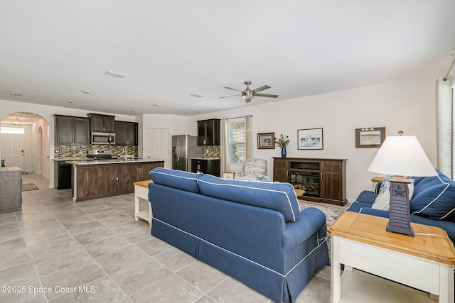 living area with visible vents, arched walkways, and ceiling fan