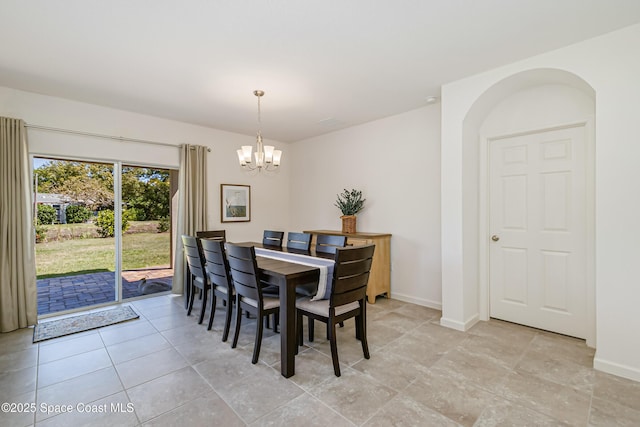 dining area with baseboards, a notable chandelier, and arched walkways