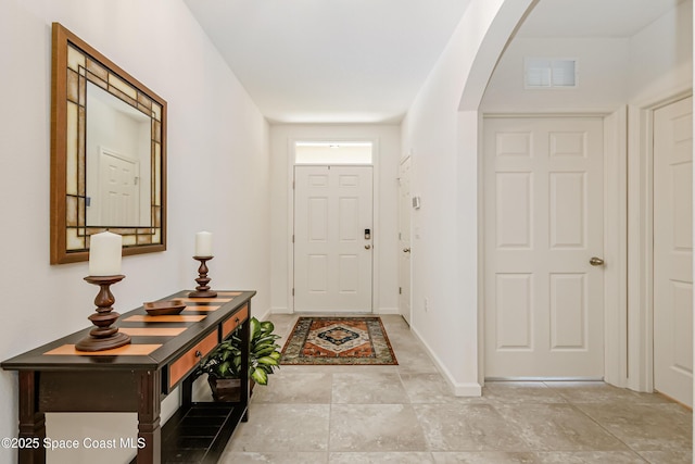 entrance foyer featuring baseboards, arched walkways, and visible vents