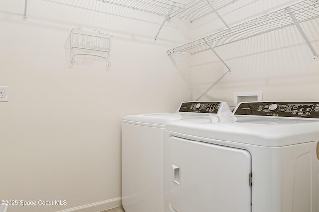 clothes washing area with laundry area, washer and dryer, and baseboards