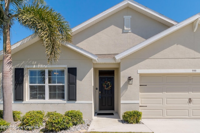 view of front of house with concrete driveway, an attached garage, and stucco siding