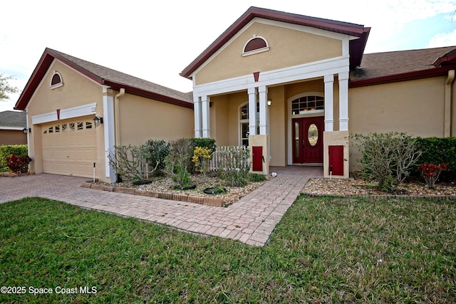 view of front facade featuring a front yard, decorative driveway, an attached garage, and stucco siding