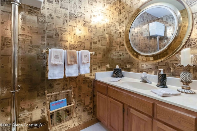 full bath with a shower stall, vanity, and wallpapered walls