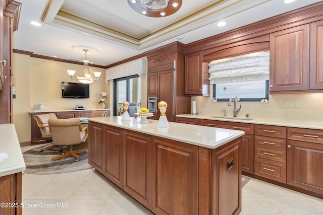 kitchen with a sink, a center island, light countertops, light tile patterned floors, and a raised ceiling