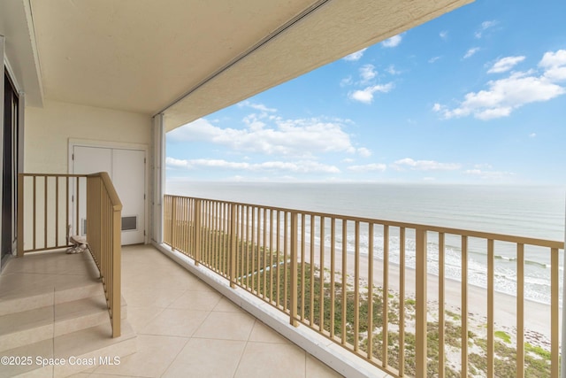 balcony featuring a view of the beach, visible vents, and a water view