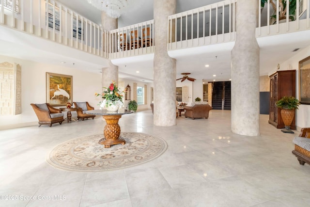 foyer entrance with a towering ceiling, a ceiling fan, and ornate columns