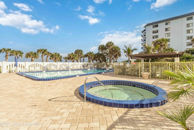 pool featuring a patio area, a community hot tub, and fence