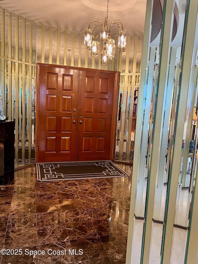 entrance foyer featuring a chandelier and marble finish floor