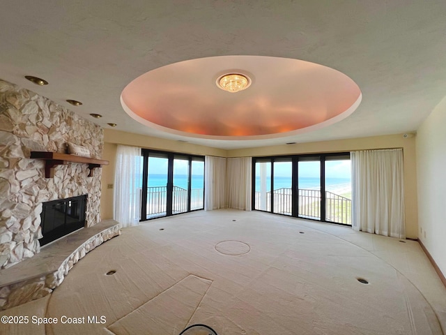 750 N Atlantic Ave Ph 4, Cocoa Beach, FL 32931 - unfurnished living room featuring light carpet, a raised ceiling, and a fireplace