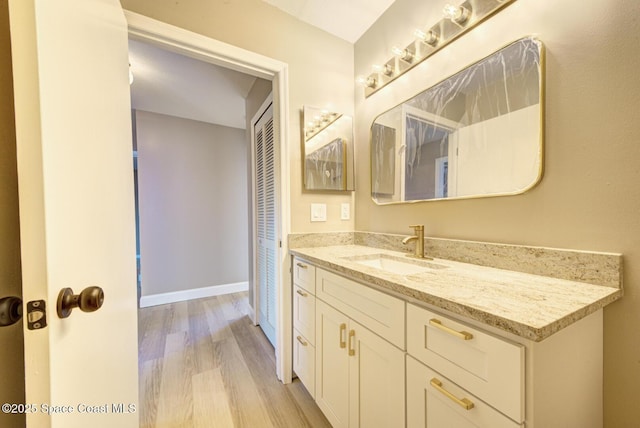 bathroom featuring baseboards, wood finished floors, and vanity