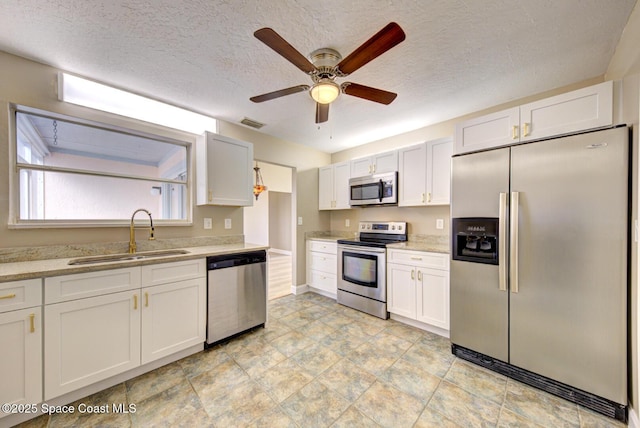 kitchen with white cabinets, a ceiling fan, appliances with stainless steel finishes, and a sink