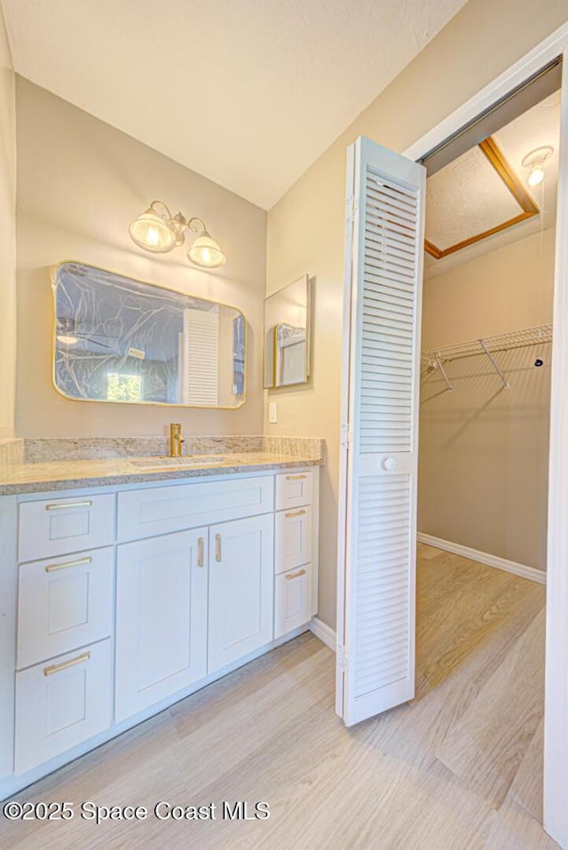 bathroom with vanity, wood finished floors, and baseboards