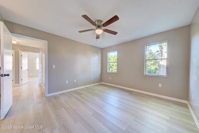 empty room featuring a ceiling fan, baseboards, and light wood finished floors