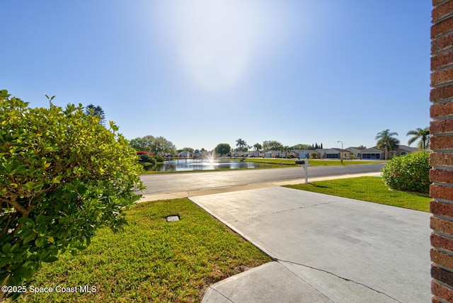 view of yard with concrete driveway and a water view