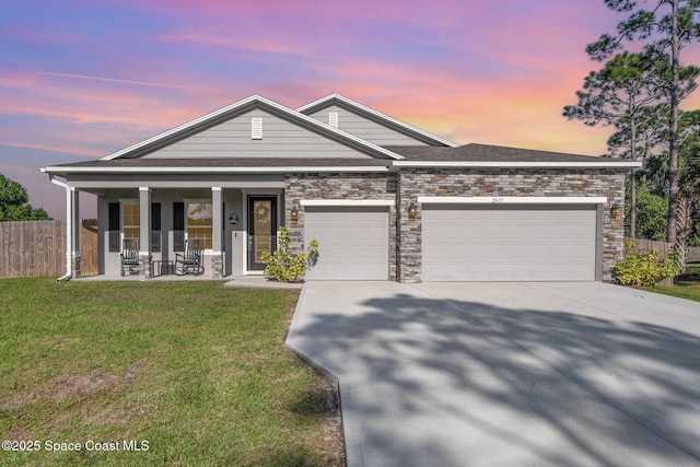 view of front of home with a front yard, fence, driveway, a porch, and a garage