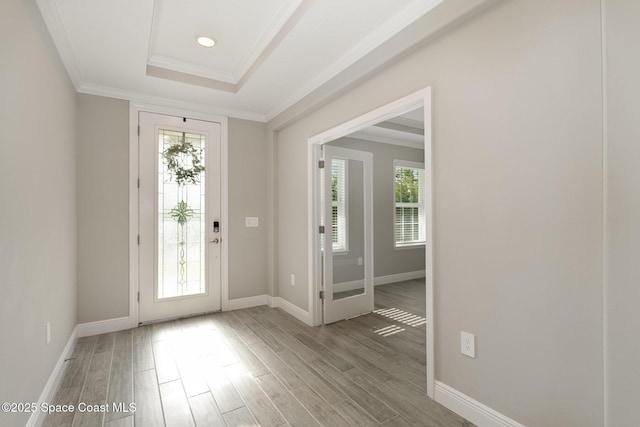 entryway featuring ornamental molding, a tray ceiling, recessed lighting, light wood-style floors, and baseboards